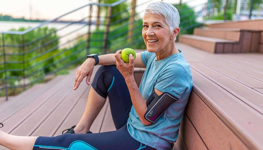 Older woman enjoying an apple while sitting on stairs, emphasizing heart health tips for a healthier lifestyle.