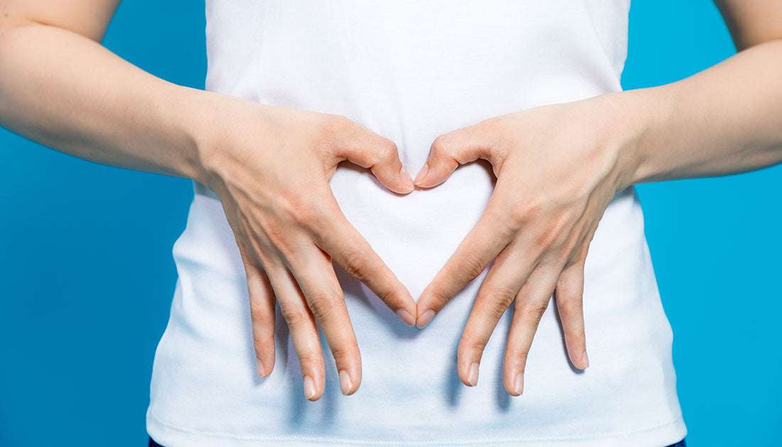Person forming a heart shape with hands over the stomach, symbolizing natural stomach healing tips 2025.