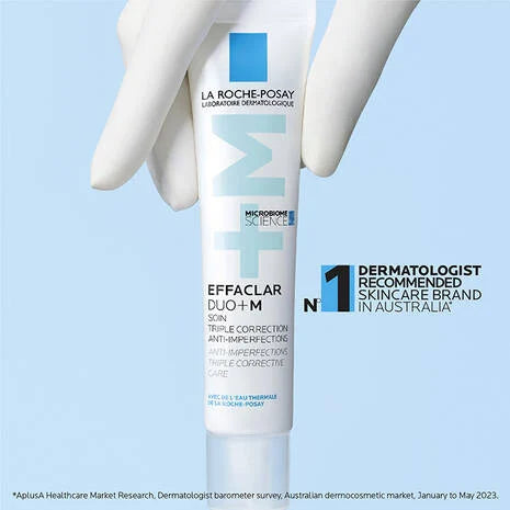 La Roche Posay Effaclar Duo+M Anti Imperfections Moisturiser 40ml tube held by gloved hand against blue background.